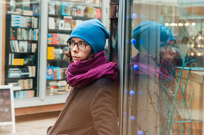 A girl waits leaning to a window of a shop at the shopping street