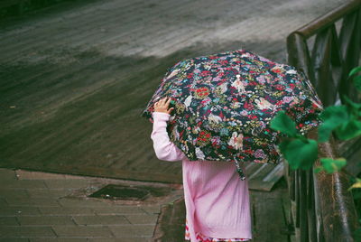 Rear view of woman with umbrella walking on wood