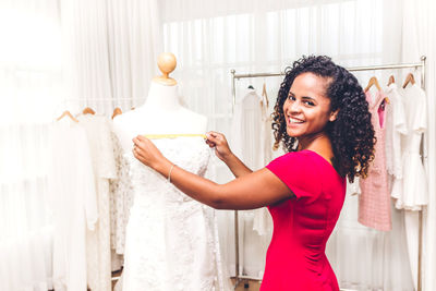 Young fashion designer measuring mannequin at home office