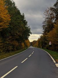 Road by trees against sky