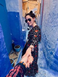 Young woman standing against blue wall