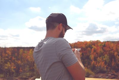 Side view of young man standing against sky