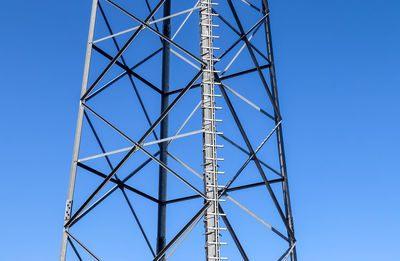 Electric antenna and communication transmitter tower in a european landscape against a blue sky