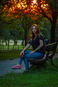 Portrait of young woman sitting on seat in park