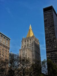 Low angle view of skyscrapers against blue sky