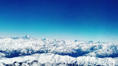 Scenic view of snow covered mountains against blue sky