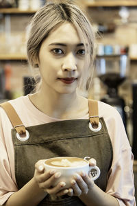 Portrait of young woman drinking coffee