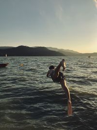 Man diving into sea during sunset