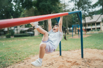 Full length of young woman swinging at playground