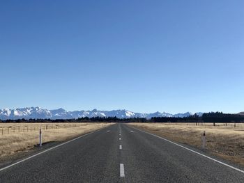 Empty road against clear blue sky