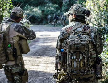 Rear view of army soldiers standing on road in forest