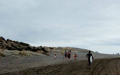 People walking on beach against sky