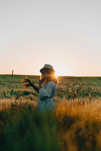 Side view of person on field against sky during sunset