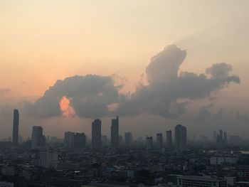 Modern buildings in city against sky during sunrise
