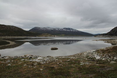 Scenic view of lake and mountains against cloudy sky