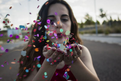 Close-up of young woman blowing confetti on road