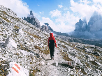 Rear view of man standing on rock against sky
