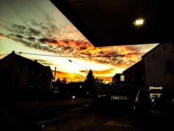 Silhouette of buildings against cloudy sky at sunset