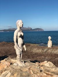 Statue by sea against clear sky