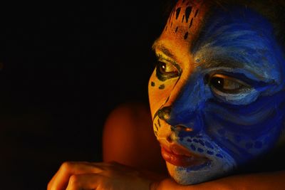 Close-up of person with face paint against black background