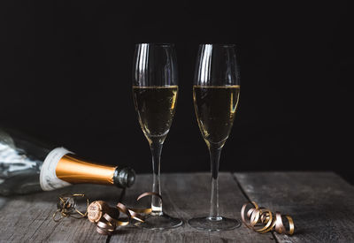 Two glasses of champagne and empty bottle with black background.