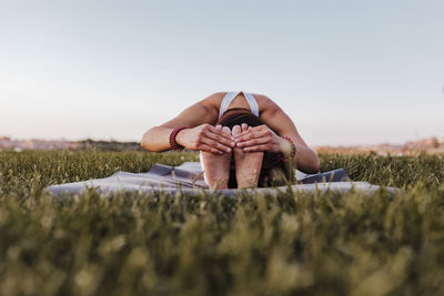 Surface level of woman exercising on field against sky during sunset