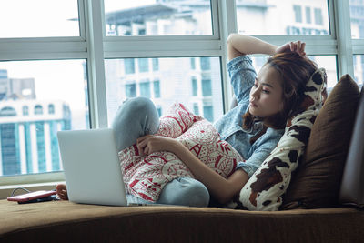 Rear view of woman using mobile phone at home