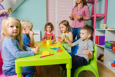 Full length of friends sitting on table