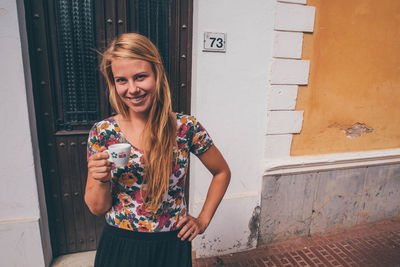 Portrait of beautiful woman standing against wall