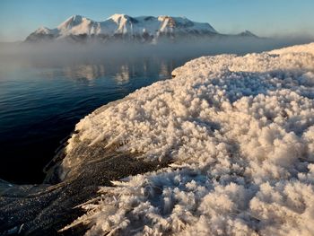 View of snow against lake and mountain range