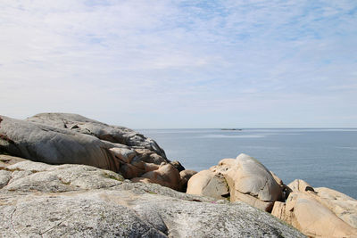 Rocks by sea against sky