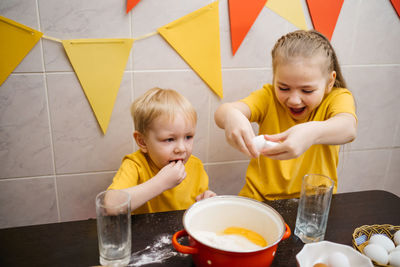 Girl breaks an egg into dough, brother helps cook, easter holiday