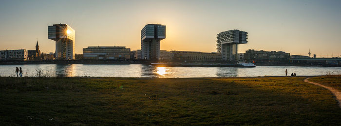 River by buildings against sky during sunset