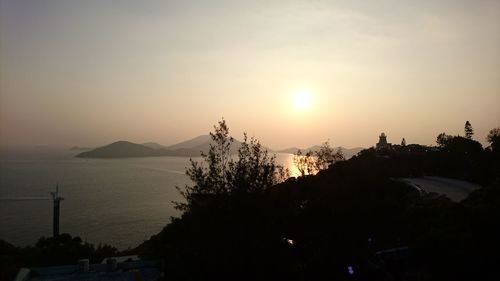 Silhouette trees by sea against sky during sunset