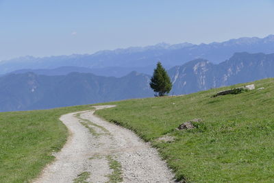 Scenic view of road amidst field against sky