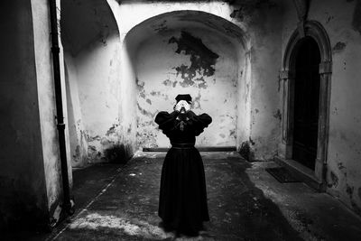 Full length of woman covering eyes while standing in abandoned building