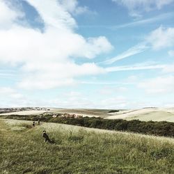 Scenic view of grassy landscape against cloudy sky