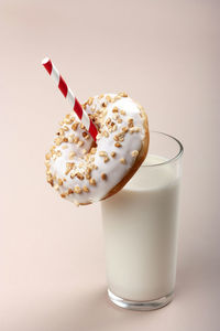 Glass of milk and donut on pink background