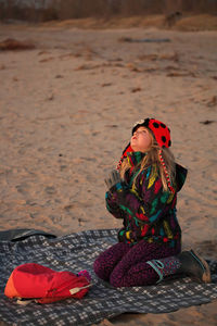 A young girl makes a wish on the first star at the beach. her hands are in a praying pose. 