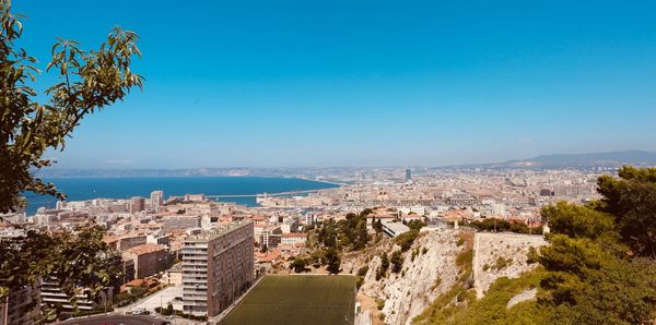 Aerial view of city by sea against clear blue sky