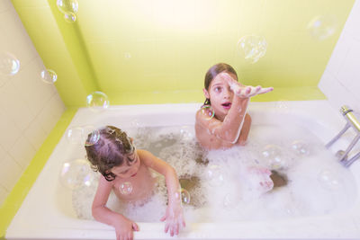 High angle view of siblings playing in bathtub