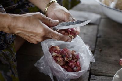 Cropped image of woman cutting onions on table at home