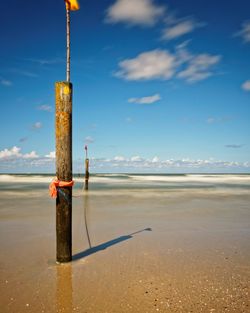 Close-up of wooden post at beach against sky