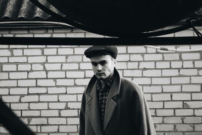 Portrait of young man standing against brick wall