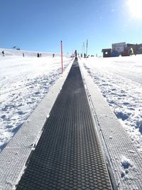 Snow covered footpath against sky in city