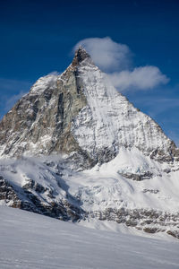 Scenic view of snowcapped mountains against blue sky