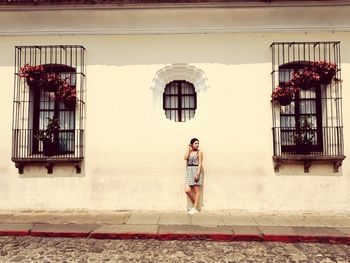 Woman standing by window of building