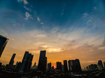 Modern buildings in city against sky during sunset