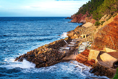 Rock formation on sea shore against sky