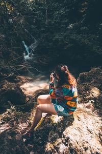 Side view of woman sitting on rock